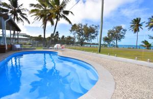 a swimming pool with palm trees and the ocean at Iluka Palms in Grasstree Beach