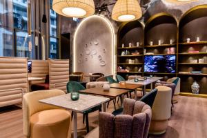 Un restaurante con mesas y sillas y un televisor. en Motel One Dresden am Zwinger, en Dresden