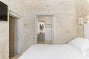 a bedroom with a white bed and a stone wall at Casetta Wilma by Wonderful Italy in Cisternino