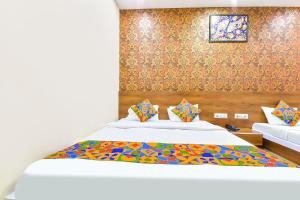a bedroom with a white bed with colorful pillows at FabHotel Raghumani Palace in Ujjain