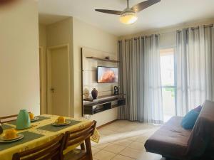 a living room with a dining table and a television at Poucos passos do mar na Praia da Costa in Vila Velha