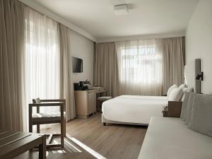 a hotel room with a white bed and a desk at Civitel Attik Rooms & Suites in Athens