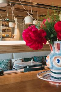 a vase with red flowers sitting on a table at Hôtel de La Plage in Biarritz