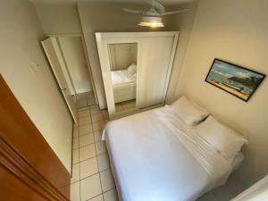 Un dormitorio pequeño con una cama y un espejo. en Poucos passos do mar na Praia da Costa, en Vila Velha
