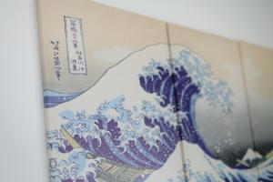 a blue and white painting of a wave on a wall at Rana片瀬江ノ島 in Fujisawa