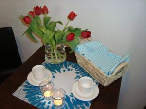 a table with a vase of red roses and a vase of glasses at Modern 2 room apartment in the city centre in Luleå