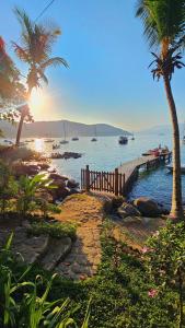 a beach with palm trees and the ocean with boats at Casa da Ilha & SPA in Abraão