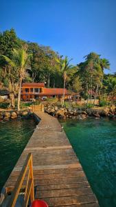 a wooden dock in the water with a house in the background at Casa da Ilha & SPA in Abraão
