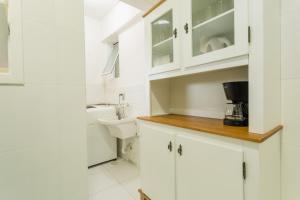 a white kitchen with white cabinets and a toilet at Apartamento Charmoso no Centro da Cidade P957 in Florianópolis +17 photos