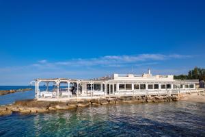a white building on a dock in the water at La Peschiera in Monopoli