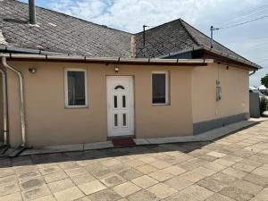 a small yellow house with a white door at Széchenyi vendégház in Sajószöged +3 photos