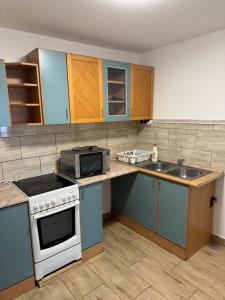 a kitchen with blue cabinets and a white stove top oven at Széchenyi vendégház in Sajószöged
