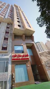 a tall building with a sign in front of it at Noor Manazil in Makkah