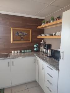 a kitchen with white cabinets and wooden walls at The Pink chair questhouse in Magaliesburg +6 photos