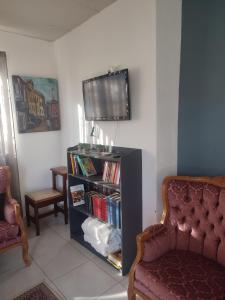 a living room with a tv and a book shelf with books at The Pink chair questhouse in Magaliesburg