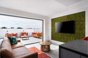 a living room with a couch and a flat screen tv at Brand new, Gwithian lodge, eco home in Praze an Beeble