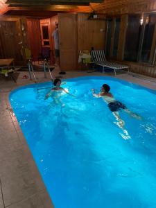 zwei Kinder schwimmen in einem großen blauen Pool in der Unterkunft Jókai 10 Vendégház Csongrád in Csongrád
