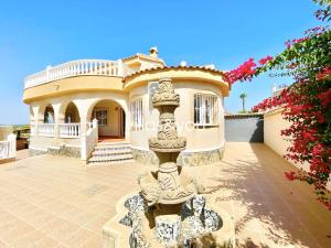 ein großes Haus mit einem Brunnen davor in der Unterkunft Villa Palmera Ciudad Quesada by Villas&You in Rojales