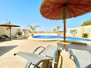 eine Terrasse mit Stühlen und Sonnenschirm und ein Pool in der Unterkunft Villa Palmera Ciudad Quesada by Villas&You in Rojales