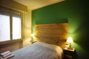 1 dormitorio con una pared verde, 1 cama y 2 lámparas en Ponte Vecchio - Guicciardini n. 10, en Florencia