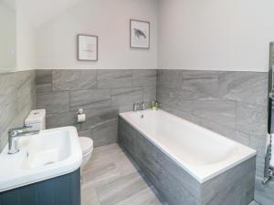 a bathroom with a tub and a toilet and a sink at The Stables in Thirsk +21 photos