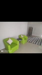 a living room with two green chairs and a laptop at Casapedian 002 Guesthouse Banda Aceh 3BR in Lheue