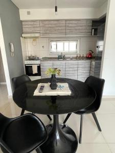 a dining room table with black chairs in a kitchen at Lovely sunset department in Morón +17 photos