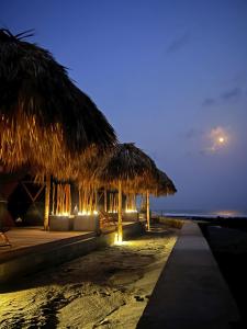 uma praia com alguns guarda-sóis de palha e o oceano em Almare Zonte - BeachFront Glamping Hotel em El Zonte