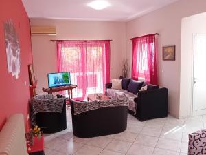a living room with a couch and a tv at White Villa in Xylokastro