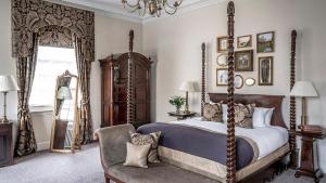 ein Schlafzimmer mit Himmelbett und Sessel in der Unterkunft Bailbrook House Hotel, Bath in Bath