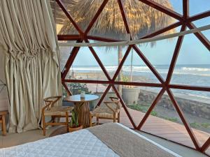 a bedroom with a bed and a view of the ocean at Almare Zonte - BeachFront Glamping Hotel in El Zonte