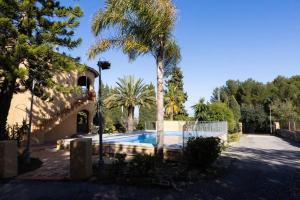 カルプにあるChalet Con Piscina Privadaのヤシの木とスイミングプールのある家