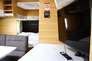 a tv in a room with a couch and a bed at Mietwohnwagen in Hörnum
