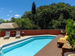 a swimming pool on a resort with chairs and trees at Apart Hotel Moderno em Joinville in Joinville