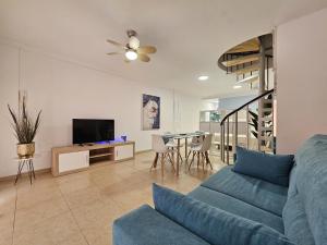 a living room with a blue couch and a tv at Appartamento Oceano - Playa San Juan in Playa de San Juan