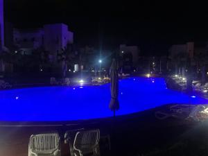 a swimming pool at night with chairs and an umbrella at Appart Cosy Résidence Perla in Saïdia