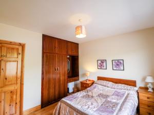 een slaapkamer met een bed en een houten kast bij An Radharc Álainn in Rosscarbery +33 foto's