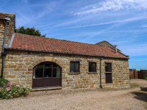 a small brick building with a brown door at Dairy Cottage in Staintondale