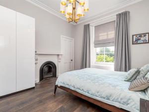スターリングにあるSpacious 4 Bedroom Flat in Stirlingの白いベッドルーム(ベッド1台、暖炉付)