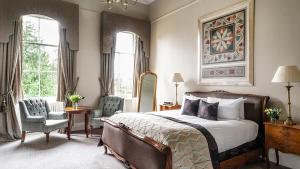 a bedroom with a bed and a chair and windows at Bailbrook House Hotel, Bath in Bath