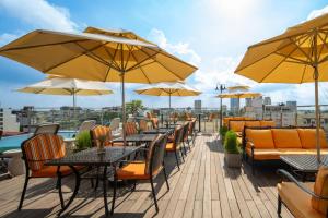 an outdoor patio with tables and chairs and umbrellas at Anatole Hotel Hanoi in Hanoi
