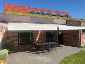a patio with chairs and a white awning on a brick building at Fleur de Ciel in Loos-en-Gohelle