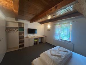 a bedroom with a bed and a desk and a window at Penzión Zemanov dvor in Lietavská Svinná