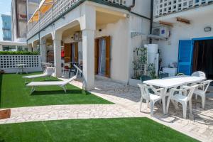 un patio avec une table et des chaises sur l'herbe dans l'établissement M407 - Marcelli, trilocale direttamente sul mare, à Marcelli