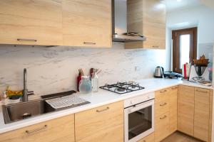 une cuisine avec des armoires en bois, un évier et une cuisinière dans l'établissement M407 - Marcelli, trilocale direttamente sul mare, à Marcelli