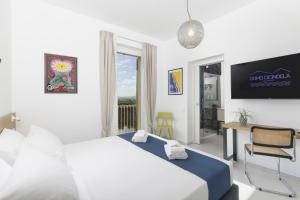 a bedroom with a bed and a desk and a window at Domo Cicindela Boutique Rooms Centro Carloforte in Carloforte