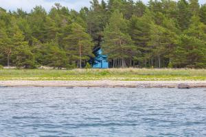 a blue house on the shore of a body of water at Dirhami jacuzzi villa in Spithami