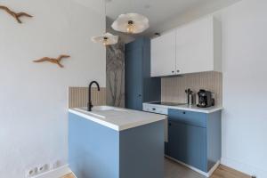 een keuken met blauwe en witte kasten en een wastafel bij Renovated 3-bedroom flat on the Grand Place in Lille