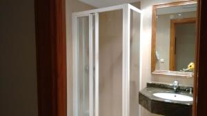 Un baño con ducha, lavabo y espejo. en Pension Larrea, en San Sebastián