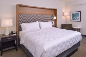 a hotel room with a large bed and a chair at Holiday Inn Detroit Northwest - Livonia by IHG in Livonia
